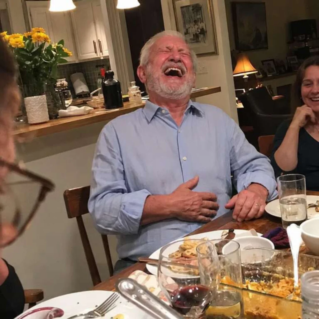 Older man laughing at a dinner table
