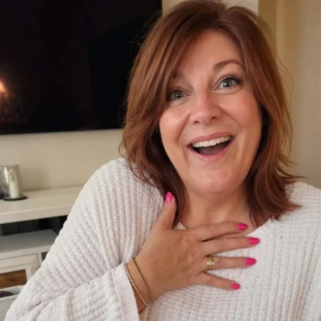 Woman smiling in surprise with one hand on her chest