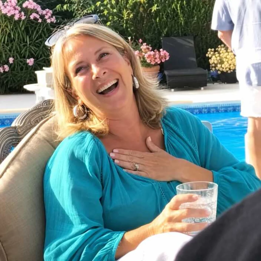Woman laughing beside a swimming pool